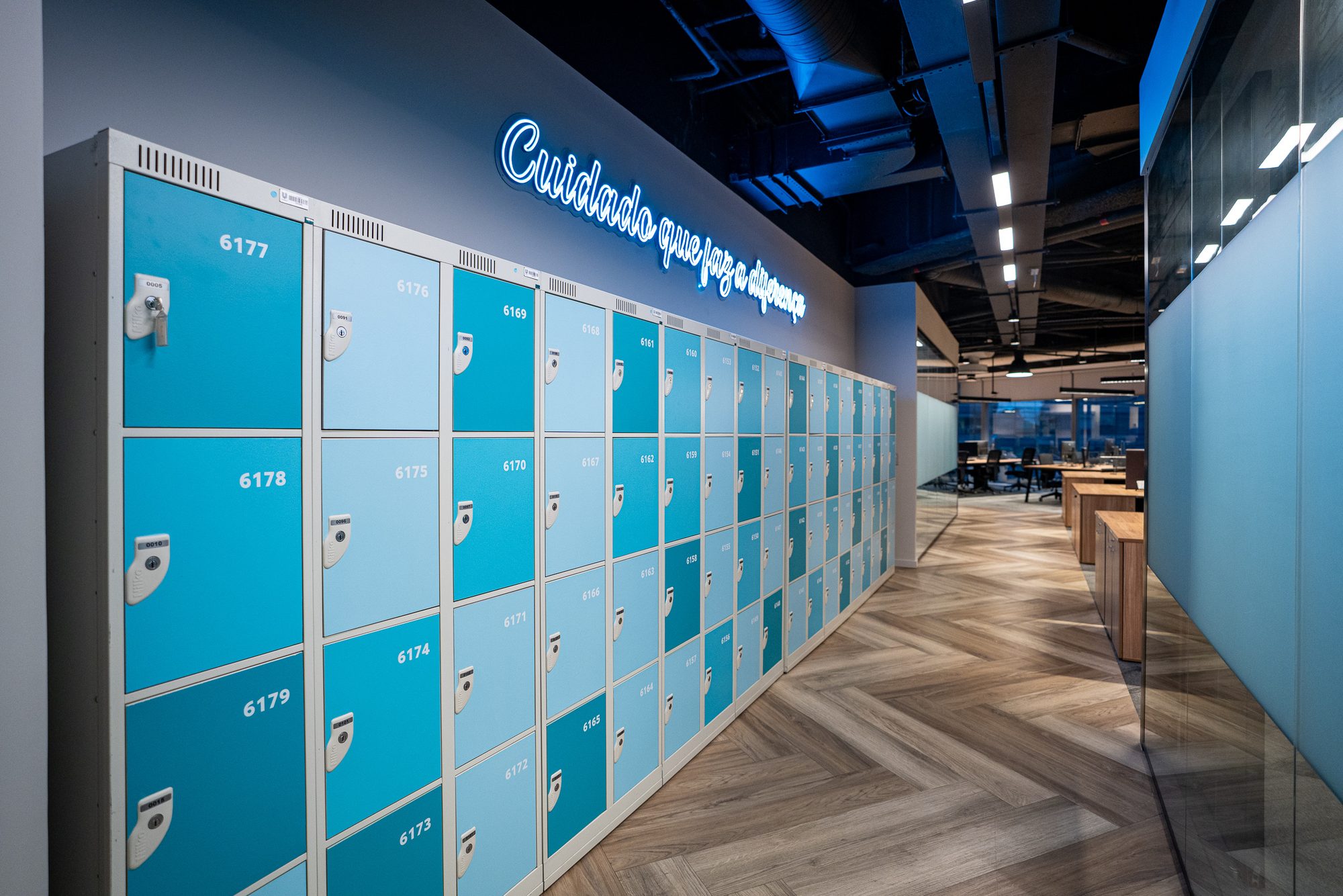 Corredor de armários da Unilever, com letreiro em neon sobre piso em espinha de peixe